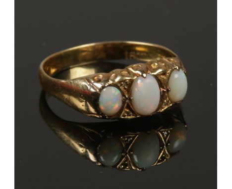 An 18ct gold, diamond and three stone opal ring. Size N 1/2. 2.15g.  Missing one diamond.