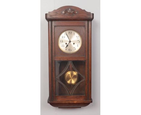 A carved oak eight day wall clock. With silvered dial and rod chiming.  Working order.