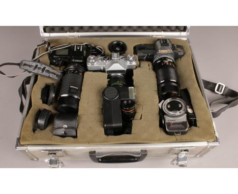 A metal camera carry case with contents. Including Canon T70 camera, Canon EOS 650 camera, Zenit-E camera, Kiron Lens, flash 