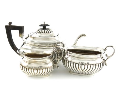 A three-piece Edwardian silver tea set, by Asprey and Co, Birmingham 1906, oblong bellied form, part-fluted decoration, scrol