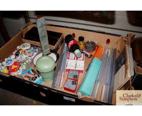 A box containing various marbles, vintage rulers, badges etc.