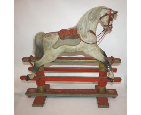 ANTIQUE ROCKING HORSE a small painted rocking horse with saddle and bridle, mounted on a painted wooden base. Some repairs in