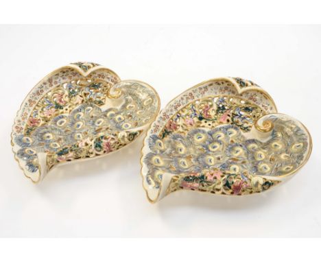 A pair of Fischer J Budapest footed shell shaped pierced bon bon dishes, with Peacock feather, hand painted and gilded design