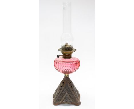 An oil lamp cast iron base with cut cranberry glass reservoir, in working order, with glass funnel.