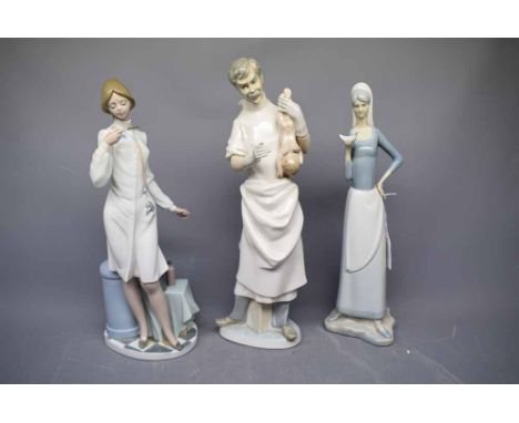 Two Lladro figures, one of a surgeon holding a baby, the other of a doctor with a stethoscope round her neck and a further Va