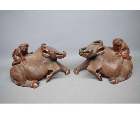 Pair of Chinese hardwood carved model of a single boy upon a recumbent buffalo, with glass eyes, each 9ins long  
