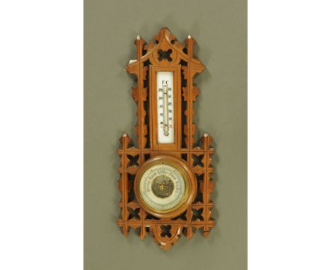 A late Victorian/ Edwardian walnut aesthetic movement aneroid barometer with thermometer.  Height 41 cm, width 19 cm.