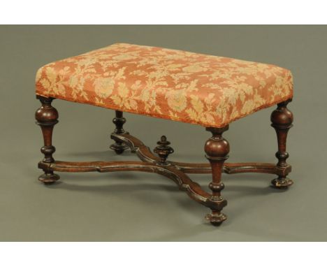 An 18th century walnut stool, with stuffover top with four turned legs united by stretchers and raised on short feet.  Height