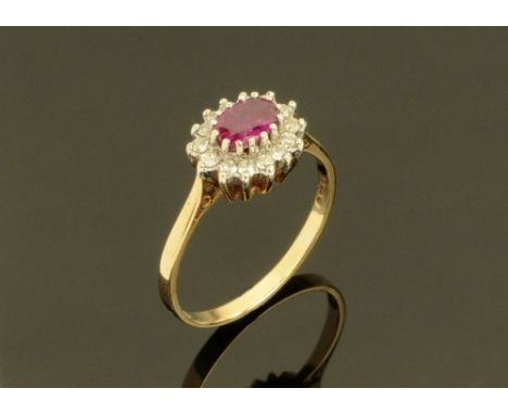 A 9 ct gold cluster ring with ruby coloured centre stone, and white stones surrounding.