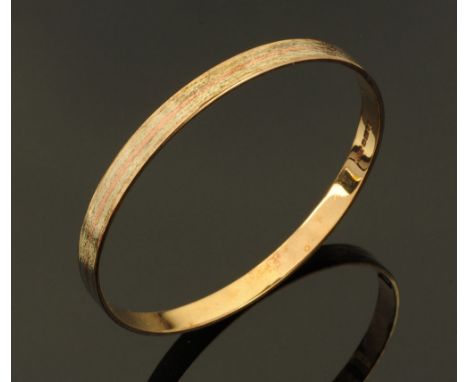 A 9 ct gold slave type bangle, with multi coloured gold inlay and textured finish, London hallmark 1982 maker A.C. Co.  Width