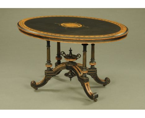 A Victorian oval aesthetic movement inlaid and ebonised centre table, with four turned and fluted supports above legs termina