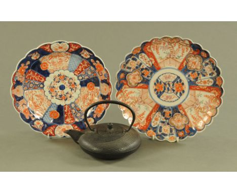 A Japanese iron squat teapot with loop handle, diameter +/- 18 cm, height 15 cm together with two Imari dishes.  Largest diam