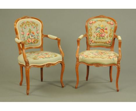 A pair of early 20th century French walnut open armchairs, with wool work tapestry backs and seats and raised on cabriole fro