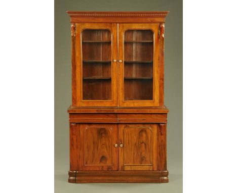 A Victorian rosewood bookcase on cupboard, with moulded cornice above a pair of glazed doors flanked on either side by flat p