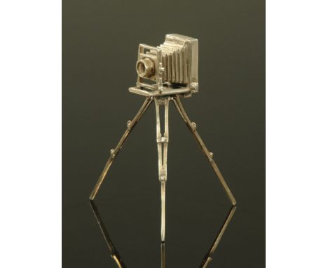 A miniature silver model of a vintage camera on tripod stand, stamped 925.  Height 9 cm.