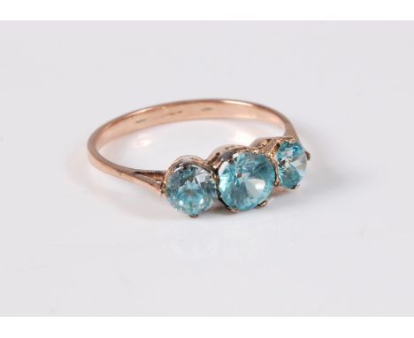 A three stone zircon ring, the three graduated round blue zircons, overall width 12mm, claw mounted to plain unmarked band (t