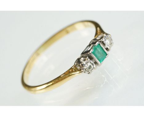 18ct gold emerald and diamond three stone ring. The ring being set with a step cut emerald flanked by two single cut diamonds