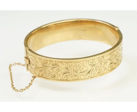 9ct gold hallmarked bangle bracelet having a hinged mechanism and engraved foliate details to the sides. Hallmarked Birmingha