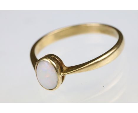 Yellow gold and opal single stone ring bezel set with an oval opal cabochon to a plain band with pinked shoulders. Unmarked, 