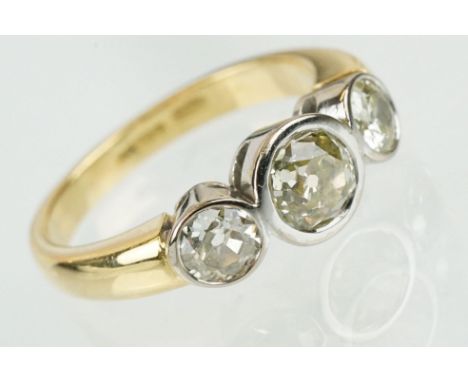 18ct gold and diamond three stone ring. The ring having three round old cut diamonds in bezel settings on an a plain yellow g