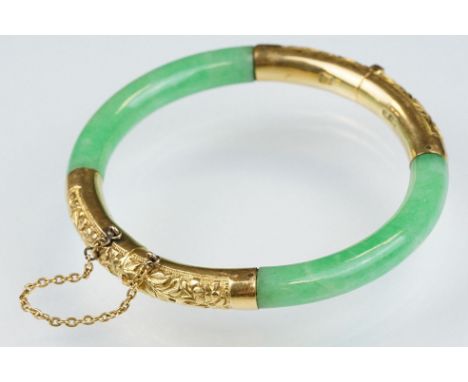 Chinese jade and gold hinged bangle bracelet. The bracelet of round form with gold hinge section and clasp section, each bein