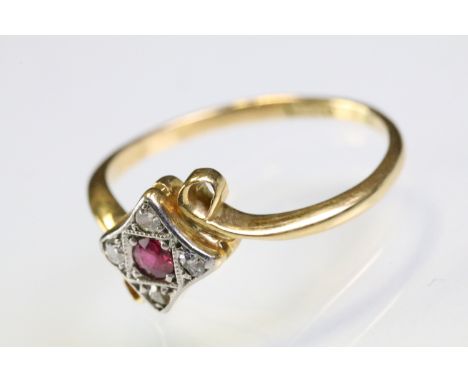 18ct gold ruby and diamond panel ring having a round cut ruby to centre surrounded by four diamond chips within a scrolled cr