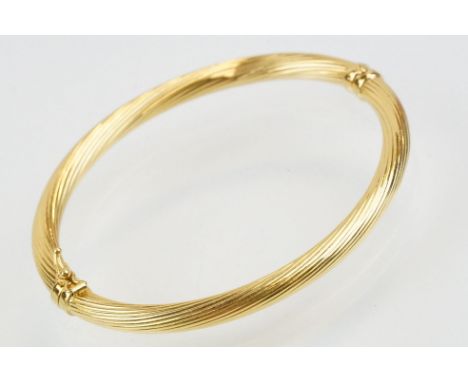 Hallmarked 18ct gold hinged bangle bracelet having a reeded twist design with catch to the clasp. Measures 6cm wide. 