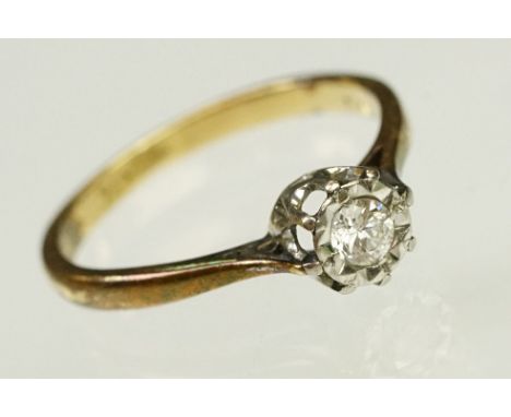 Diamond solitaire ring being set with a round brilliant cut diamond in an illusion setting, mounted to a yellow gold shank. D