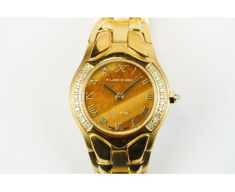 Klaus-Koberc Decorum gold plated wrist watch having a tigers eye style dial, with diamonds set to the bezel and mounted onto 