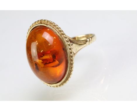 9ct gold hallmarked amber ring being set with an oval amber cabochon in a rub over setting. Hallmarked London. Size R. 