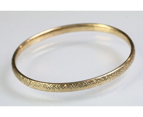 9ct gold hallmarked bangle bracelet having a textured exterior. Import marked 1990. Interior width 6cm wide. 