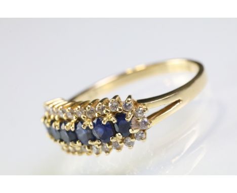 18ct gold sapphire and diamond line ring. The ring being set with six oval cut sapphires surrounded by diamond accent stones.