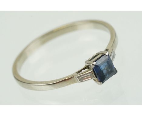 Sapphire and diamond three stone ring set with a step cut blue sapphire flanked by two baguette cut diamonds. Metal unmarked.