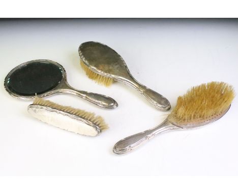 Early 20th Century silver backed dressing table set having moulded scrolled edges to each, comprising two hair brushes, cloth