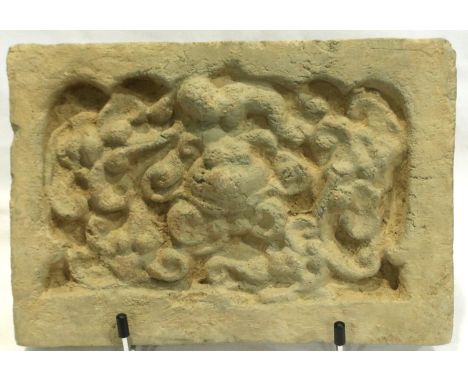 A Song Dynasty red clay tile, decorated in relief with a stylised front-facing dragon, 18 x 26 cm. P&amp;P Group 2 (£18+VAT f