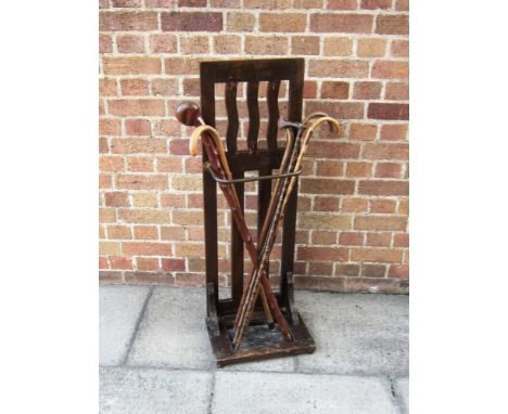 SIX ASSORTED WALKING STICKS contained in an oak stick stand