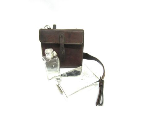 A LEATHER HUNTING CANTEEN with straps for saddle mounting and containing a plated sandwich case and glass flask with plated s