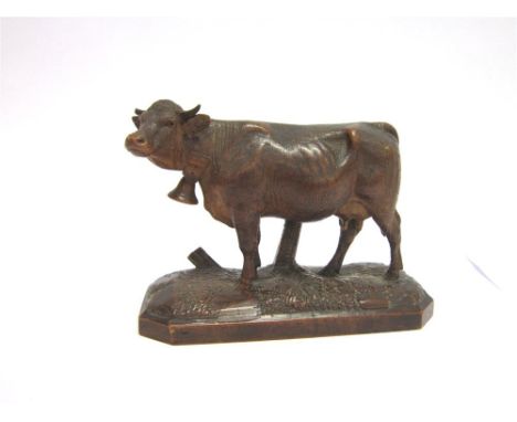 A BLACK FOREST WOODEN CARVED FIGURE OF A COW a bell around her neck, on a shaped rectangular base, 17cm long