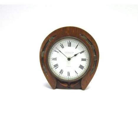 A NOVELTY DESK CLOCK  with a carved oak horse-shoe shaped surround, the circular white dial with black Roman numerals and mar