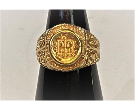 A yellow metal signet ring with elaborate scroll decoration to shoulders, the top with incised seal for M, 11.94gm, size J/K,