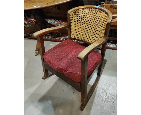 A 1930's rocking armchair with low seat and cane back; a reproduction rocking armchair with stick back; a reproduction dwarf 