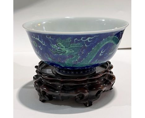 A Chinese mottle blue ground bowl with green dragon decoration, bearing seal mark to base, diameter 15.5cm on wooden stand. 