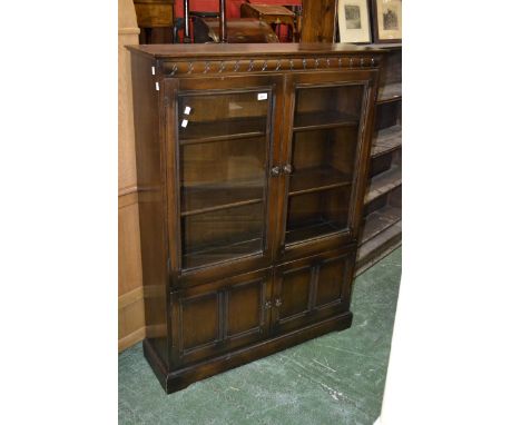 An Ercol style bookcase, two glazed doors enclosing shelving over two door cupboard, plinth base. 138cm high x 101cm wide.