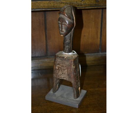 Tribal Art - an African figural heddle pulley, probably Baule, carved with a mask, 23cm high, museum type display stand 