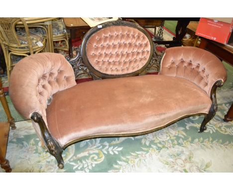 A Victorian sofa, deep button oval back, scrolling arms, carved forelegs.