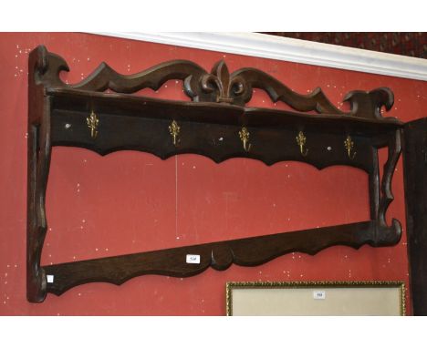 An early 20th century oak wall mounted kitchen shelf with five hooks for a graduated set of saucepans