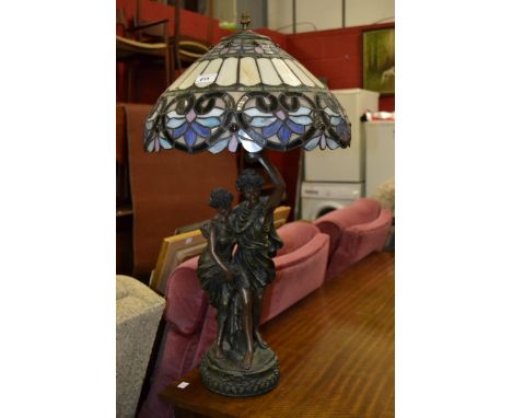 A large figural table lamp with stained glass Tiffany type shade.