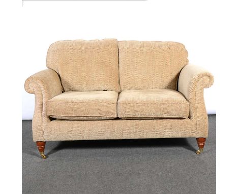 Parker Knoll two-seat settee and matching wingback armchair, stained wood supports on gilt casters; sofa width 152cm, depth 8