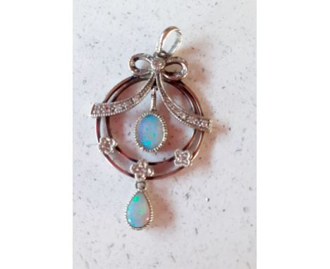 An early 20th Century white gold pendant having a ribbon design of small diamonds above 2 opal teardrops and 3 floral diamond