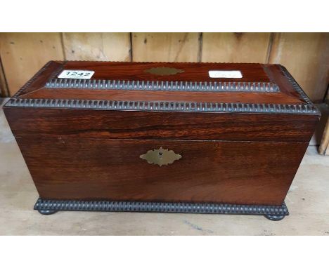An early 19th Century rosewood tea caddy of sarcophagus form, fitted with pair of lidded removable compartments and with cent